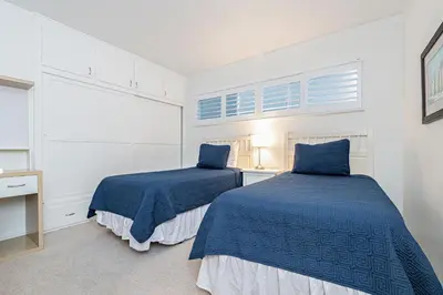 two beds in a white room with blue sheets at Bayfront 2Br With Harbor Views, Only Steps To The Sand By Beachview Rentals in Newport Beach