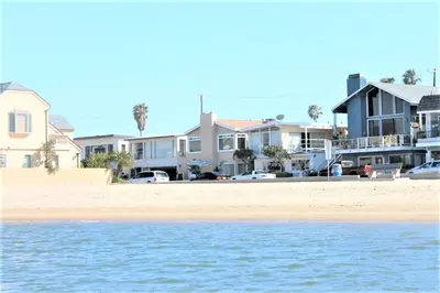 a group of houses on the beach with the water at Bayfront 2Br With Harbor Views, Only Steps To The Sand By Beachview Rentals in Newport Beach