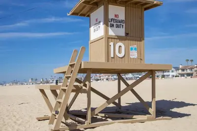 a lifeguard tower on the beach with a wooden bench at Bayfront 2Br With Harbor Views, Only Steps To The Sand By Beachview Rentals in Newport Beach