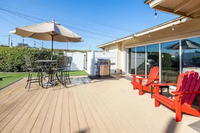 a deck with a table and chairs and an umbrella at Walk To Ponto Beach - Surf and Relax in Carlsbad
