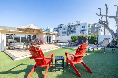 two red chairs and a table on a lawn at Walk To Ponto Beach - Surf and Relax in Carlsbad