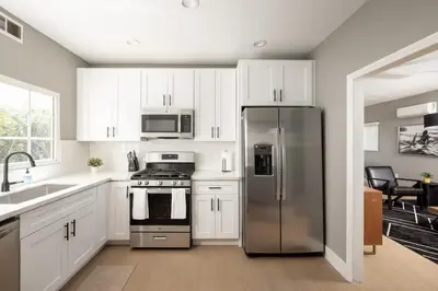 a kitchen with white cabinets and a stainless steel refrigerator at The Urban Den by Coastline Vacation Rentals in San Diego