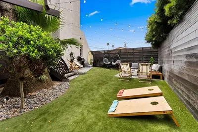 a small backyard with a lawn with two surfboards on it at Nomad Surf Lounge by Coastline Vacation Rentals in San Diego