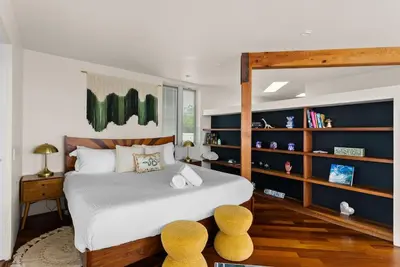 a bedroom with a large bed with yellow stools at Nomad Surf Lounge by Coastline Vacation Rentals in San Diego