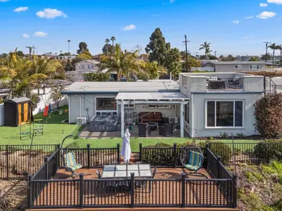 a house with a deck with chairs and a yard at The Lookout by Coastline Vacation Rentals in Chula Vista