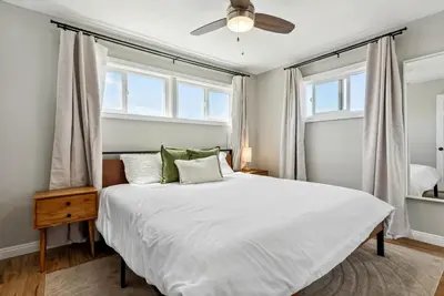 a bedroom with a white bed with a ceiling fan at Bohemian Seaside by Coastline Vacation Rentals in San Diego