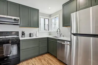 a kitchen with green cabinets and a stainless steel refrigerator at Bohemian Seaside by Coastline Vacation Rentals in San Diego