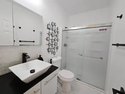 a white bathroom with a sink and a shower at Modern Marble Retreat Private Gated ADU with Laundry & Parking in National City