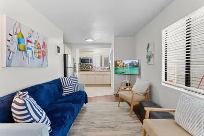 a living room with a blue couch and a kitchen at The Sands by Coastline Vacation Rentals in San Diego