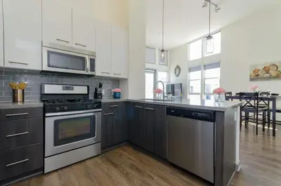 a kitchen with stainless steel appliances and a table at Snazzy 2BR Near Petco Park & Convention Center in San Diego