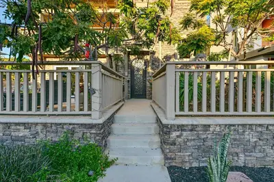 a wooden gate to a house with stairs at Stroll to Shore Oceanside Condo with Hot Tub Access in Oceanside