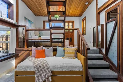 a room with a bed with pillows and a staircase at Vintage Surf Hut by Coastline Vacation Rentals in San Diego