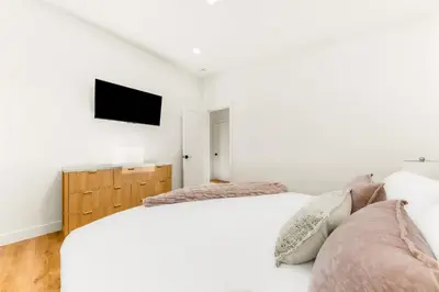 a bedroom with two beds and a tv on the wall at PB Beach Compound - 2 New Homes Steps to Sand in San Diego