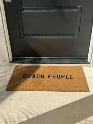 a door with a door mat that reads beach people at South O Surf House by Coastline Vacation Rentals in Oceanside