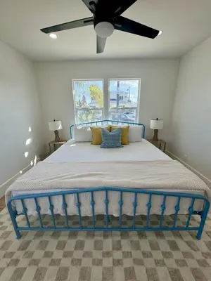a blue bed in a bedroom with a ceiling fan at South O Surf House by Coastline Vacation Rentals in Oceanside