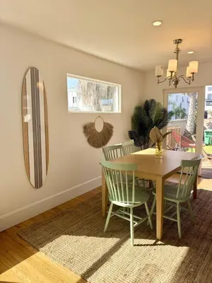 a dining room with a table and chairs and a mirror at South O Surf House by Coastline Vacation Rentals in Oceanside