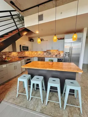 a kitchen with a counter and stools in it at Penthouse Industrial Loft & Parking Little Italy in San Diego
