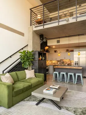 a living room with a green couch and a table at Penthouse Industrial Loft & Parking Little Italy in San Diego