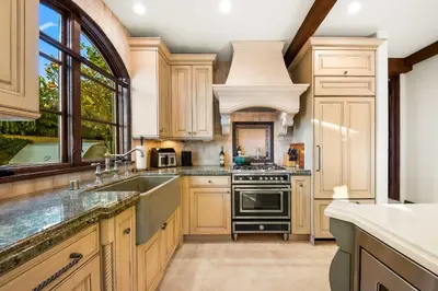 a kitchen with wooden cabinets and a sink and an oven at The Stratford - Del Mar Luxury Living in San Diego
