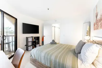 a white bedroom with a bed and a tv at Pier-View Penthouse Condo in Pacific Beach in San Diego