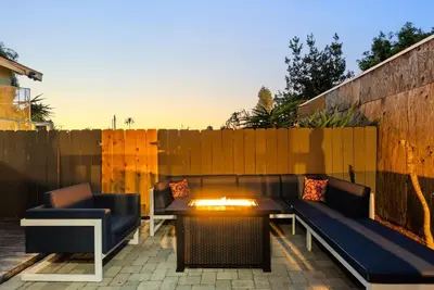 a patio with a couch and a table and a fence at The Treehouse by Coastline Vacation Rentals in San Diego