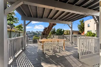 a wooden deck with a table and chairs on it at The Treehouse by Coastline Vacation Rentals in San Diego