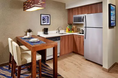 a kitchen with a table and a refrigerator at Homewood Suites by Hilton San Diego Mission Valley/Zoo in San Diego