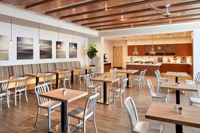 a restaurant with wooden tables and chairs and a kitchen at Homewood Suites by Hilton San Diego Downtown/Bayside in San Diego
