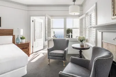 a bedroom with a bed and two chairs and a table at Blue Lantern Inn, A Four Sisters Inn in Dana Point