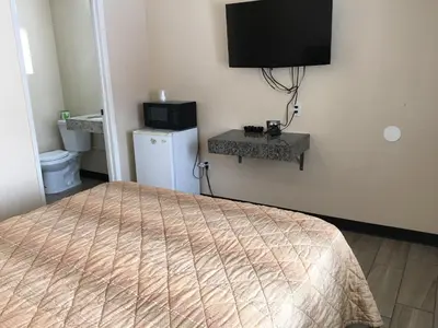 a bedroom with a bed and a television on the wall at Ace Budget Motel in San Diego