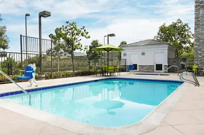 a swimming pool with chairs and an umbrella at SpringHill Suites San Diego Rancho Bernardo/Scripps Poway in Poway