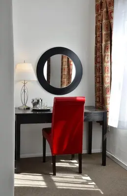 a red chair sitting in front of a desk with a mirror at El Primero Boutique Hotel in Chula Vista