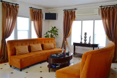 a living room with an orange couch and a piano at El Primero Boutique Hotel in Chula Vista