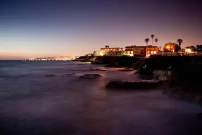 a beach at night with buildings and the ocean at The Inn at Sunset Cliffs in San Diego