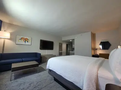a hotel room with a bed and a blue couch at Holiday Inn Express San Diego South - Chula Vista by IHG in Chula Vista