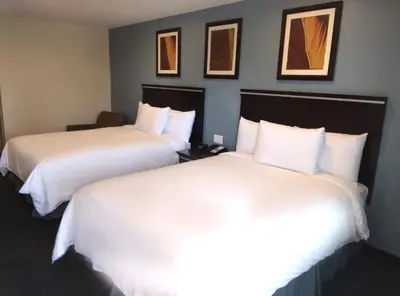 two beds in a hotel room with white sheets at SureStay Hotel by Best Western Chula Vista San Diego Bay in Chula Vista
