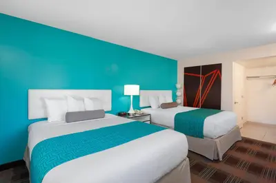 two beds in a hotel room with a blue wall at Howard Johnson by Wyndham San Diego Hotel Circle in San Diego