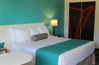 a hotel room with a large bed with a green and white blanket at Howard Johnson by Wyndham San Diego Hotel Circle in San Diego