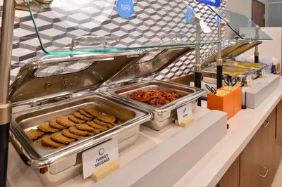 a buffet line with trays of food on a counter at Holiday Inn Express Mira Mesa San Diego by IHG in Mira Mesa