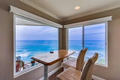 a dining room with a table and chairs and a large window at Work Friendly Oceanfront SURF25 Condo in Solana Beach