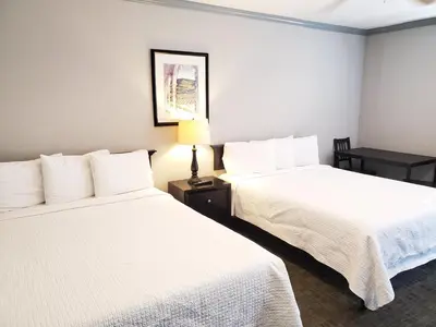 two beds in a hotel room with white sheets at Coronado Inn in San Diego