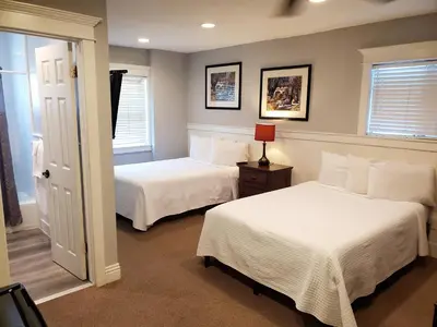two beds in a room with two windows at Coronado Island Inn in San Diego