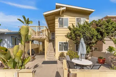 a house with a deck and a table and an umbrella at Sweet Sunset Studio in San Diego