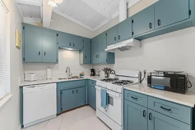 a blue kitchen with white appliances and blue cabinets at Sweet Sunset Studio in San Diego