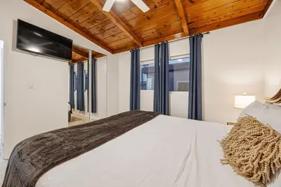 a bedroom with a white bed and windows at Mimi's & Nana's Beach House in San Diego