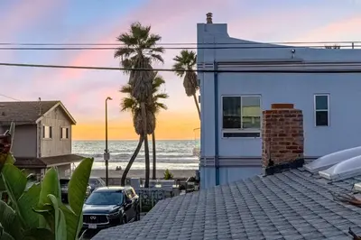 a house on the beach with palm trees and the ocean at Mimi's & Nana's Beach House in San Diego