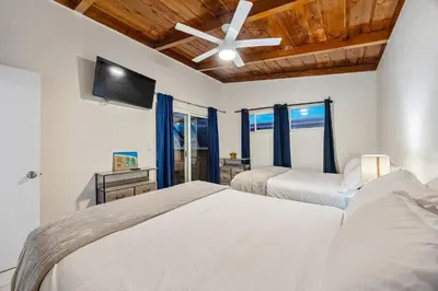 two beds in a bedroom with a ceiling fan at Mimi's & Nana's Beach House in San Diego