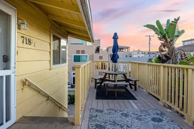 a wooden deck with a table and an umbrella at Mimi's & Nana's Beach House in San Diego