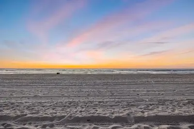 a beach at sunset with a person in the water at Mimi's & Nana's Beach House in San Diego