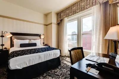 a hotel room with a bed and a desk and window at Gaslamp Plaza Suites in San Diego